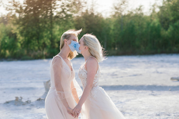 Lesbian couple wedding on white sand, wear masks to prevent epidemic COVID-19 - Photo, Image