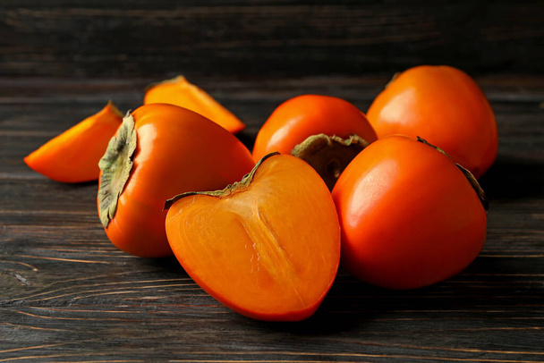 Fresh ripe persimmon on wooden background, close up - Фото, изображение