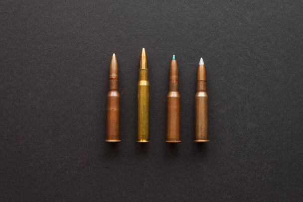 Négy különböző töltény egy sötét hátterű puskához. - Fotó, kép