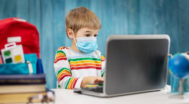 Boy in medical face protection mask indoors on blue background - Fotoğraf, Görsel