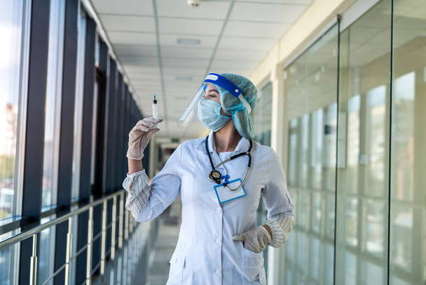 mooie verpleegster in uniform en gezichtsschild met spuit en wachtende vaccinatie in kliniek - Foto, afbeelding