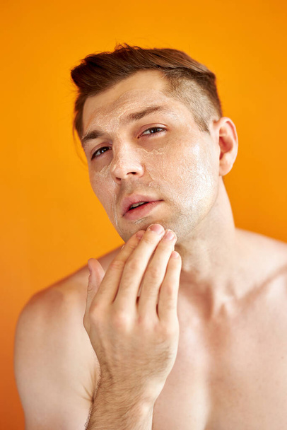 good-looking caucasian man cares for his skin, moisturizes it - Photo, image