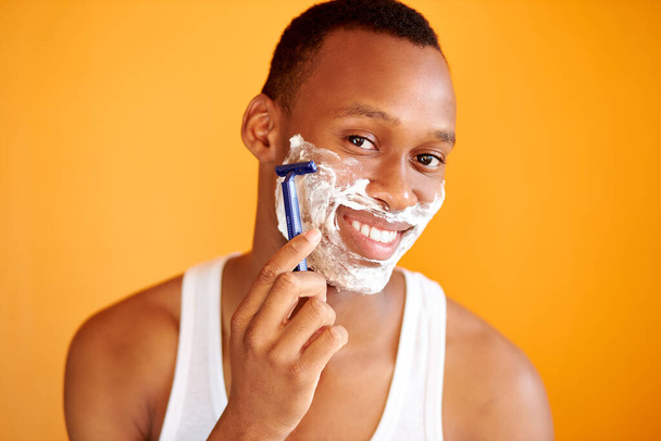 afro american on yellow background in foam shaving with a razor, portrait. - Foto, Bild