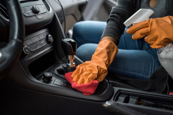 Mano con guante con toallita húmeda y limpieza antibacteriana en aerosol interior del coche  - Foto, Imagen