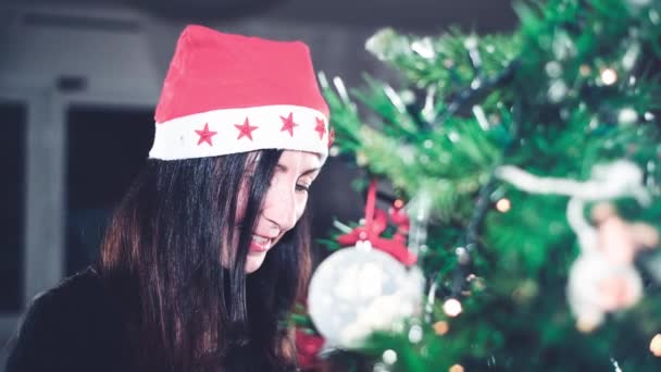 Kobieta dekorowanie choinki w domu noszenie Santa Hat - Materiał filmowy, wideo
