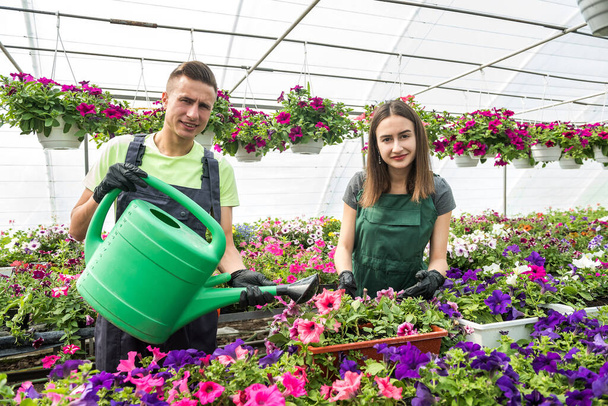 Dva mladí květinářství pracující s květinami v průmyslové skleníkové školky - Fotografie, Obrázek