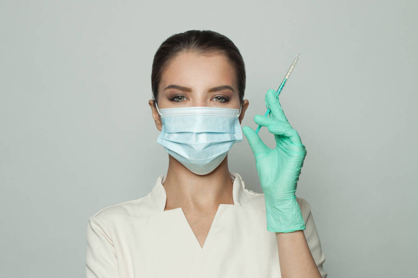 Portré orvos visel professzionális egyenruha kezében fecskendő a kezében fehér háttér. Orvostudomány, kozmetológia és vakcinázás - Fotó, kép