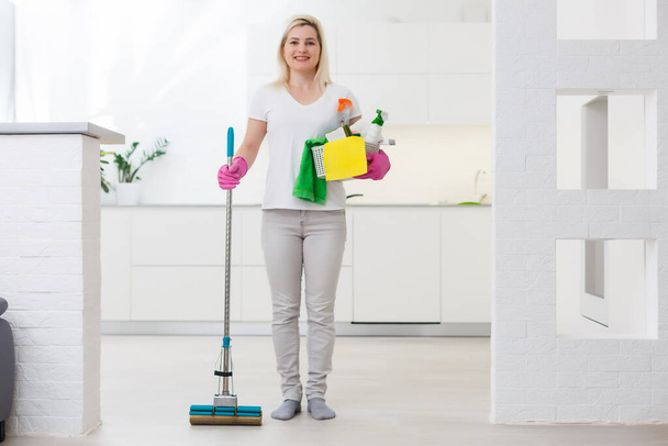 Vrouw met dweil en emmer met schoonmaakmiddelen thuis - Foto, afbeelding