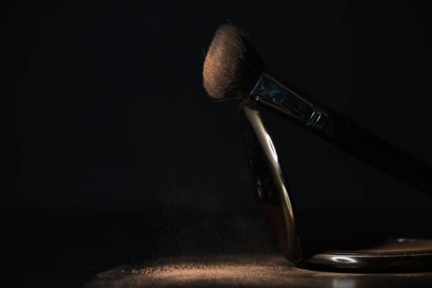 escova de maquiagem com pó caindo no fundo preto - Foto, Imagem
