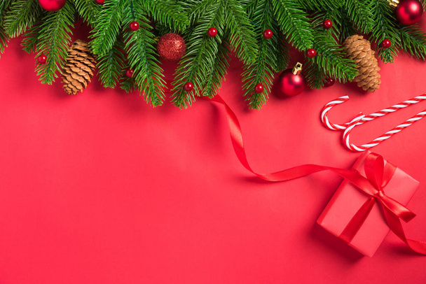 Рождественский праздник фон с подарком коробки украшения композиция, Верхний вид елки зеленые ветви елки и орнаменты на красном фоне стола - Фото, изображение