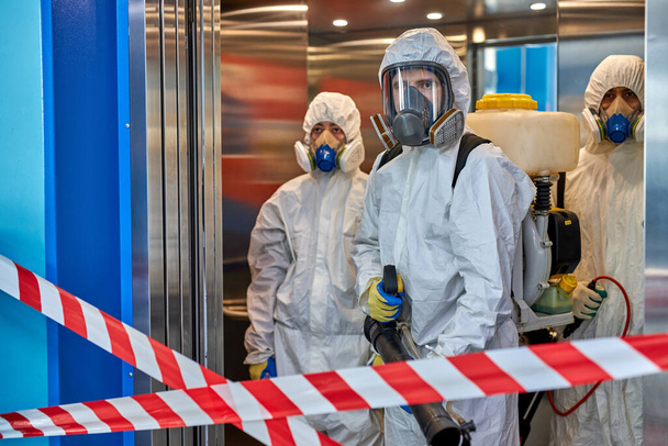 people in hazmats making cleaning in apartment building - Photo, image