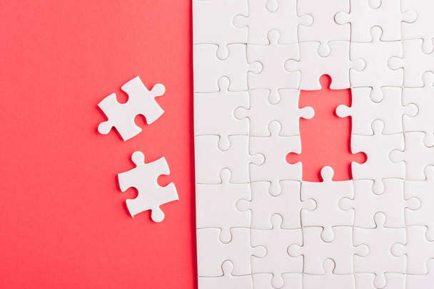 Top view flat lay of paper plain white jigsaw puzzle game texture last pieces for solve and place, studio shot on a red background, quiz calculation concept - Photo, image