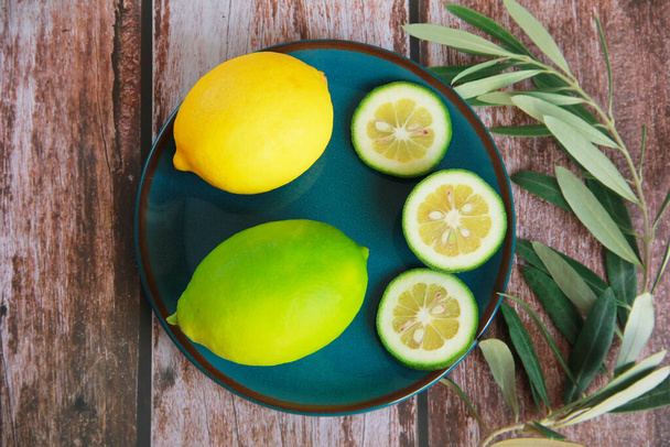 přírodní žlutý citron a kulaté citrónové plátky na dekorativním talíři - Fotografie, Obrázek