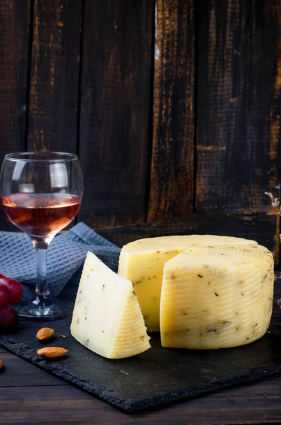 homemade cheese head with lavander on old dark wooden board and glass of wine on table. Fresh dairy product, healthy organic food. Delicious appetizer. - Фото, изображение