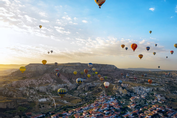 Early morning in the valley with rocks and balloons in the sky at dawn. View from a height of the city and houses. Cappadocia. Turkey. Goreme. - Φωτογραφία, εικόνα