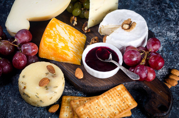Assorted homemade pieces cheese with jam, grapes, cookies and nuts, cookies and nuts on table.  Fresh dairy product, cheese snack, healthy organic food. Delicious appetizer. - Foto, imagen