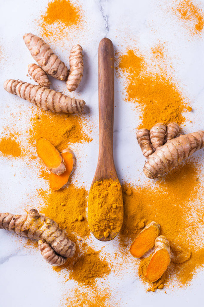 Food and drink, diet nutrition, health care concept. Raw organic orange turmeric root and powder, curcuma longa on a cooking table. Indian oriental low cholesterol spices. - Photo, Image