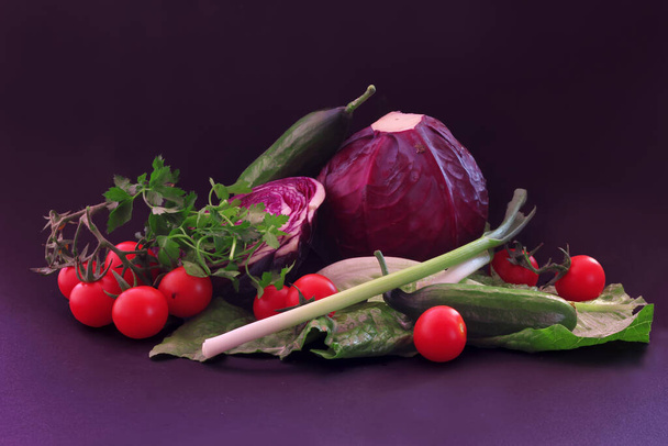 purple cabbage, tomato and lettuce leaves on a black background - Фото, изображение