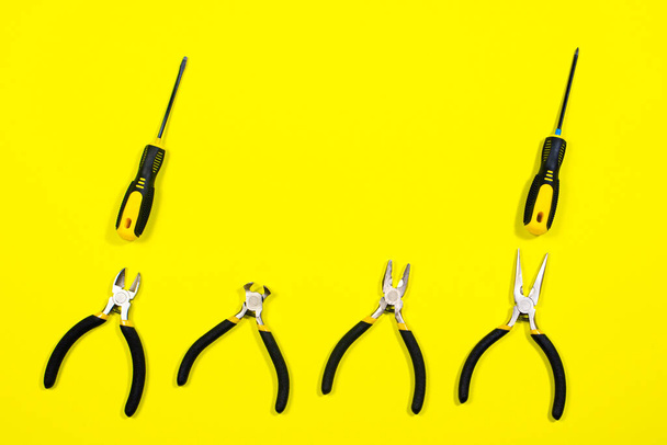 Tools on a yellow background with space for text. Screwdrivers, pliers, biters, rounds, tongs A banner for a construction store A banner for a construction store - Photo, Image