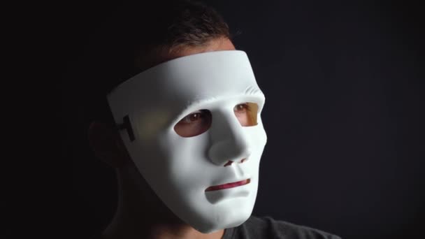 man verbergt zijn gezicht onder een wit masker - Video