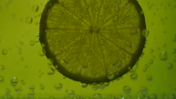 Limão em água com gás sobre fundo verde
 - Filmagem, Vídeo