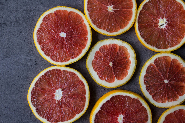 血のオレンジのマクロ写真。果物の食感が閉じます。濃い灰色の背景に赤いオレンジ色の果実円。柑橘系の食感を閉じます。ジューシーなオレンジトップビューの写真. - 写真・画像