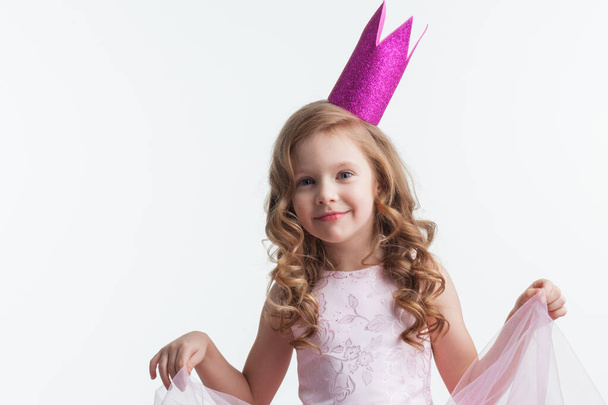 Little princess girl in pink crown and beautiful dress on white background - Fotó, kép