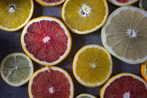 Hintergrund sind frische Zitrusfrüchte. Orange, Mandarine, Zitrone, Limette, Grapefruit auf dunklem Hintergrund. Lebendige Farben saftiger Orangen.  - Foto, Bild