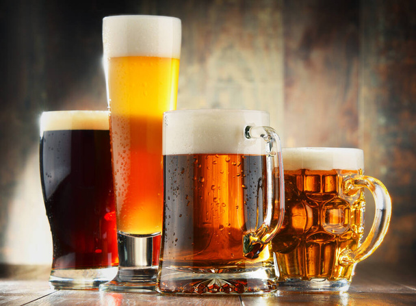 Four glassed of beer on wooden background. - Фото, изображение