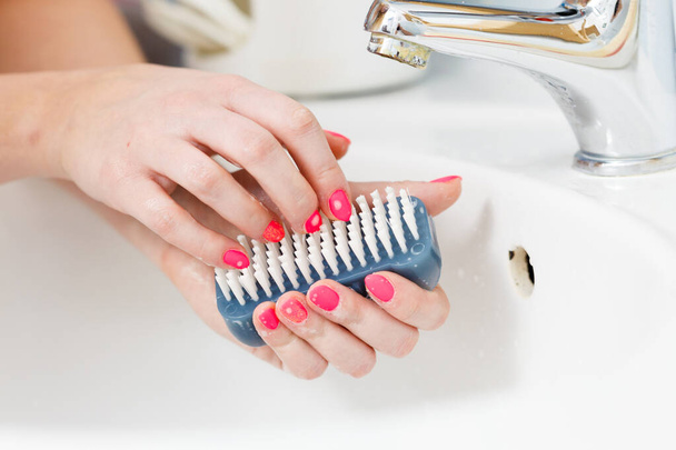 Woman washing her hands in sink to get rid of germs using brush. Prevent coronavirus epidemic. - Photo, Image