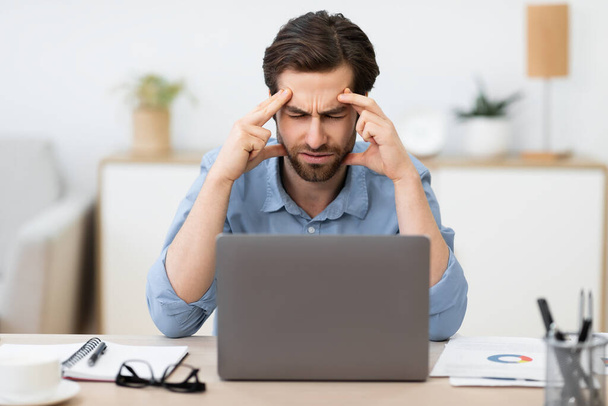 Δυστυχισμένος επιχειρηματίας που υποφέρει από πόνο στο κεφάλι κάθεται στο γραφείο - Φωτογραφία, εικόνα