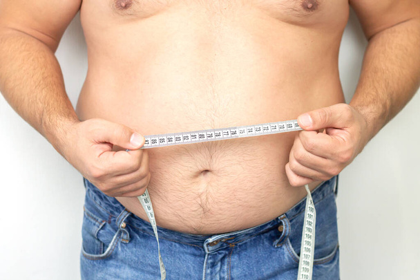 Gordo hombre con gran estómago wering jeans celebración de su cinta métrica - Foto, Imagen