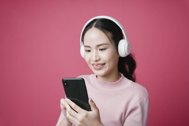 Ritratto di giovane donna asiatica che cerca canzone su un'applicazione di streaming musicale. - Foto, immagini