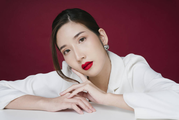 Retrato de hermosa joven mujer asiática con traje de chaqueta blanca aplicado lápiz labial rojo. - Foto, imagen