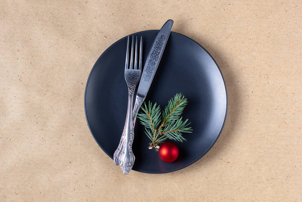 Ajuste de mesa de vacaciones con rama de árbol de Navidad, plato vacío y decoraciones. Año nuevo plano concepto de alimentos laicos sobre fondo artesanal - Foto, Imagen