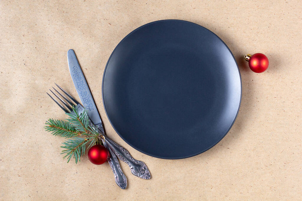 Holiday table setting with branch of christmas tree, empty plate and decorations. New year flat lay food concept on craft background - Φωτογραφία, εικόνα