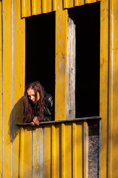 Kobieta wychylająca się przez stare okno - Zdjęcie, obraz
