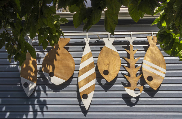 Декоративная рыба из дерева различных форм и размеров на сером фоне - Фото, изображение