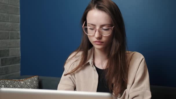 Traurige Frau arbeitet Laptop-Computer zu Hause. Eine unglückliche Kaukasierin benutzt zu Hause einen Laptop. Besorgter Mädchen-Stress bei freiberuflicher Arbeit am heimischen Arbeitsplatz. Aufgebrachte Frau blickt auf Laptop-Bildschirm. Mädchen - Filmmaterial, Video