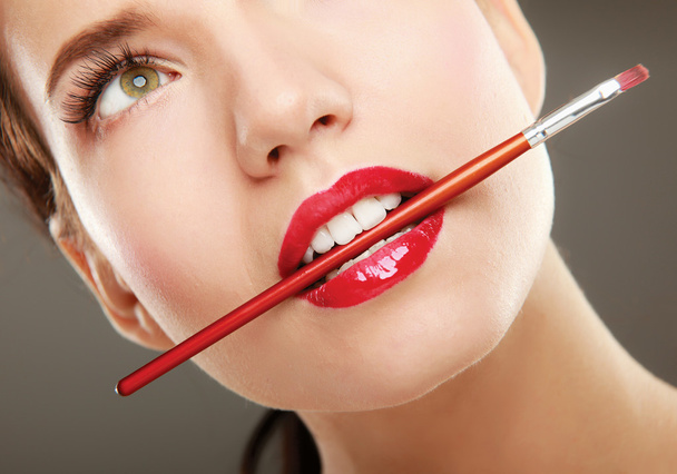 Woman's lips holding make up brush - Фото, изображение