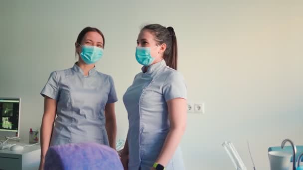 Dos hermosas mujeres jóvenes doctores en máscaras médicas están hablando y sonriendo. Concepto de Salud y Medicina. Movimiento lento. - Imágenes, Vídeo