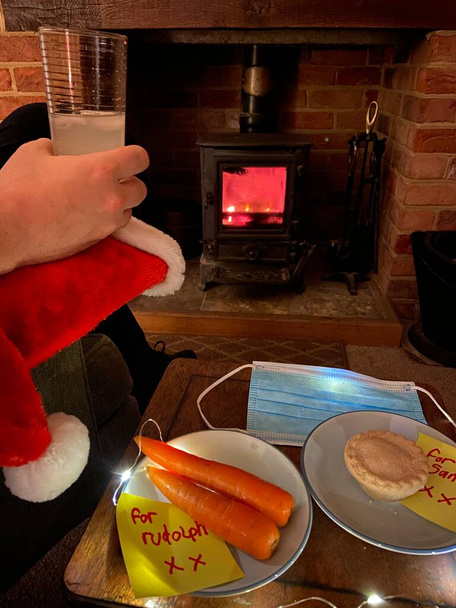 covid-19 Veille de Noël, chapeau de Père Noël avec masque facial et pour note de Père Noël avec tarte fine et carottes pour Rudolph dans la note d'écriture pour enfants   - Photo, image