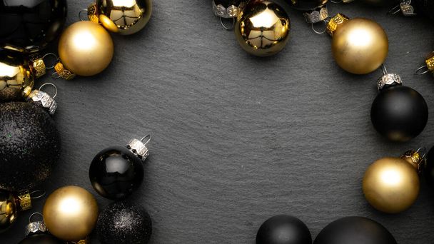 Design de inverno. Decoração de bugigangas de Natal de ouro em fundo preto texturizado com espaço de cópia. Deitado plano, vista superior. - Foto, Imagem