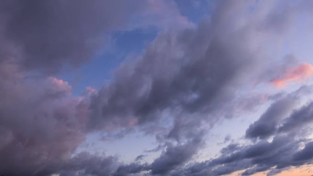 Buenas tardes. Sobre el fondo del cielo azul, nubes rosas y púrpuras, iluminadas por el sol poniente. Pantalla completa - Foto, imagen