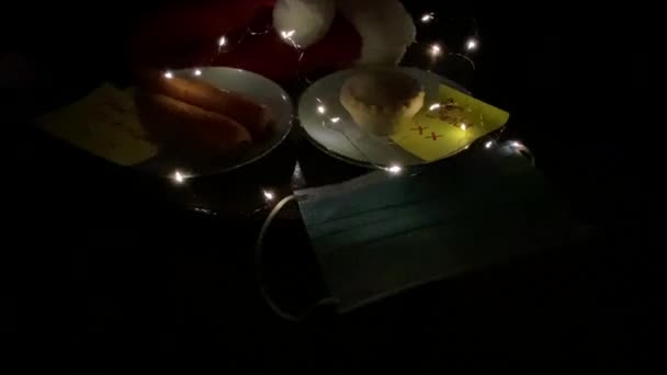 covid-19 Heiligabend, Weihnachtsmütze mit Gesichtsmaske und für Weihnachtsmann Notiz mit Hackfleischkuchen und Karotten für Rudolph in Kinderschrift Notiz   - Filmmaterial, Video