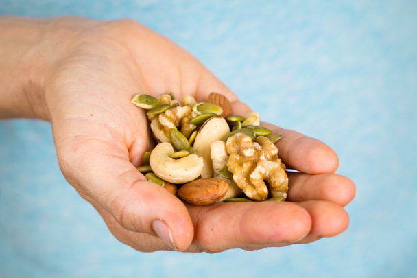 ruka držící různé ořechy a semena - Fotografie, Obrázek