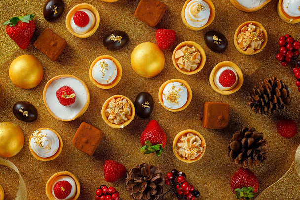 Selección de deliciosos postres navideños presentados sobre fondo dorado - Foto, Imagen