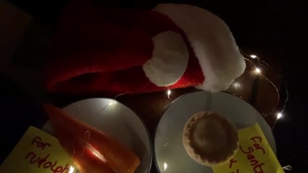 covid-19 véspera de Natal, chapéu de santa com máscara facial e para nota de Santa com torta de carne picada e cenouras para Rudolph na nota de escrita infantil   - Filmagem, Vídeo