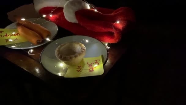 covid-19 véspera de Natal, chapéu de santa com máscara facial e para nota de Santa com torta de carne picada e cenouras para Rudolph na nota de escrita infantil   - Filmagem, Vídeo