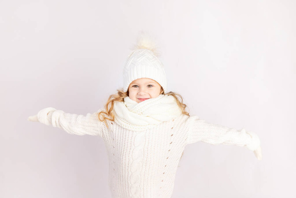 Sıcak şapkalı ve süveterli mutlu bir kız çocuğu beyaz arka planda, mesaj için yer var. - Fotoğraf, Görsel